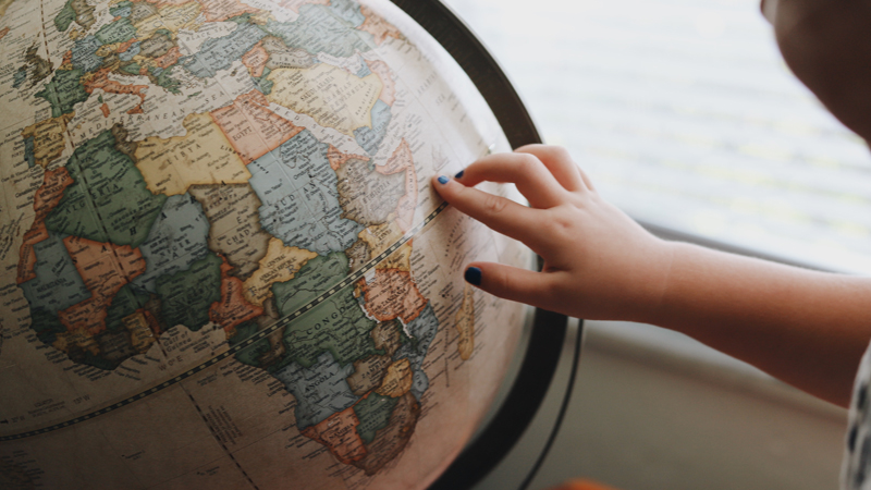 Hand pointing to countries on globe
