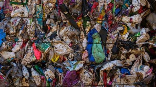 A large pile of garbage sitting next to a metal fence
