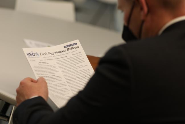 A delegate reads the Earth Negotiations Bulletin (ENB) to keep up to date with the meeting