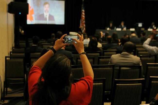 A participant takes a photo during the address made by Steven Guilbeault, Minister, Environment and Climate Change, Canada