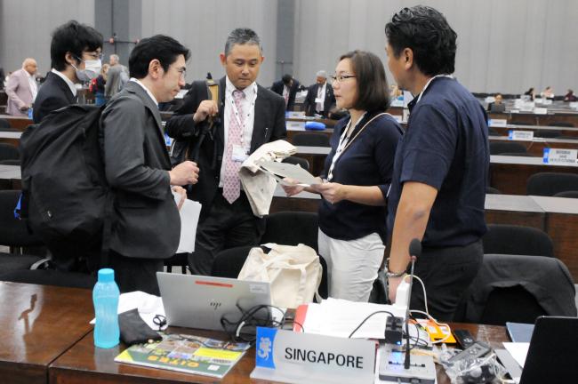 Delegates from Singapore confer before the start of the Committee session