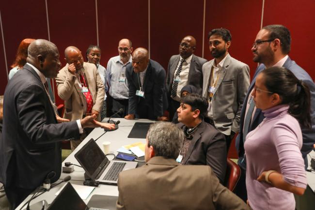 Sam Adu-Kumi, Co-Chair, Contact Group on SC Compliance, huddles with delegates during the contact group