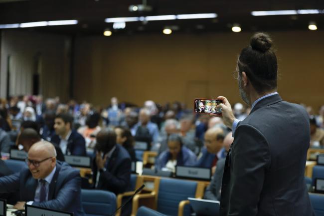 A delegate taking a photo of the plenary room