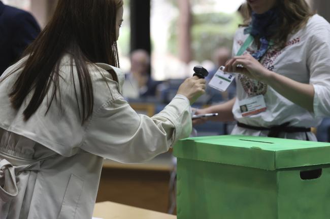 A secretariat member scanning a delegate's voting badge 