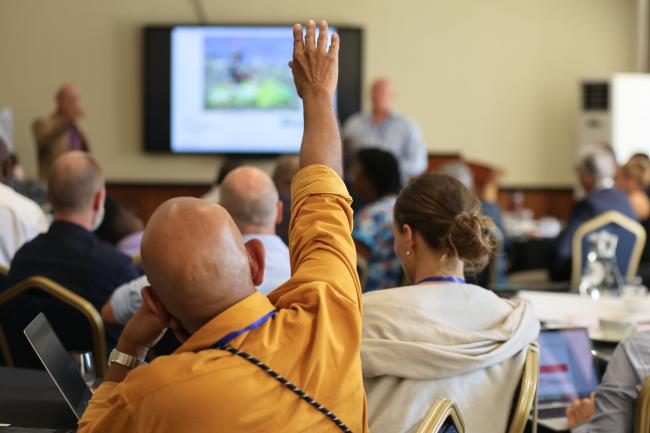 A participant raises his hand to pose a question 