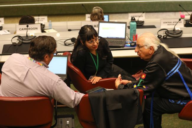 Kenneth Atsenhaienton Deer, Kahnawake Mohawk Territory (right), speaks with delegates from Canada