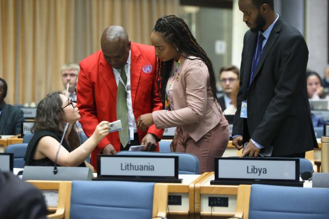 A teller with members of the Secretariat checking the credentials delegates