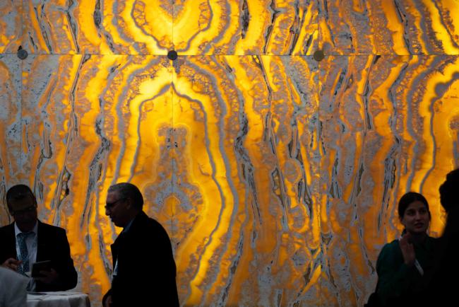Participants between sessions by a back-lit marble wall