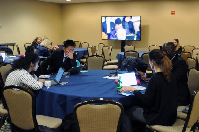 Participants follow the proceedings outside the meeting room