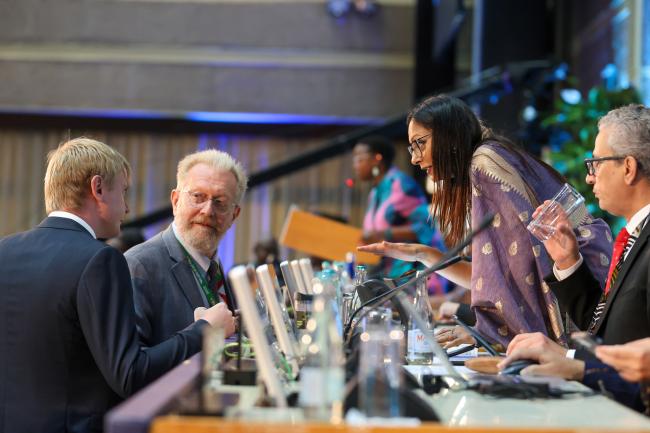 Petr Antipov and Dmitry Maksimychev, Russian Federation, conferring with Radhika Ochalik, Secretary, Governing Bodies and Stakeholders, UNEP