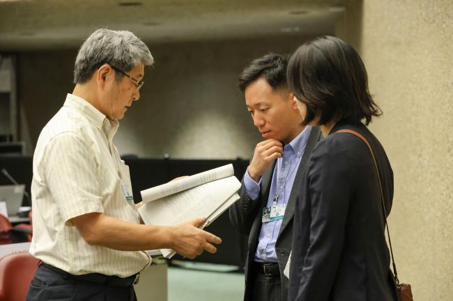 Delegates review the discussed documents during a short break in the session.
