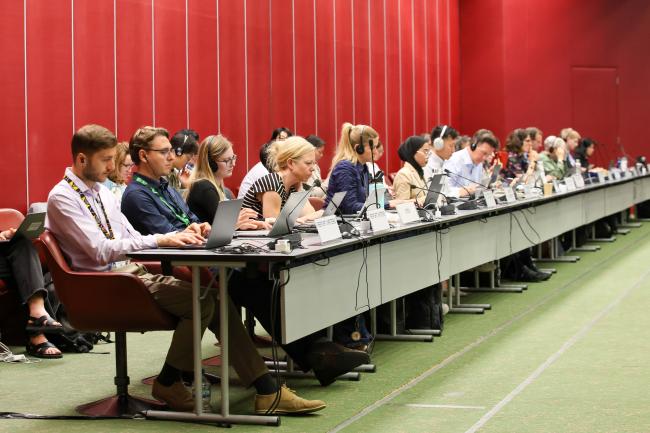 Observers follow the process from the back of the room 
