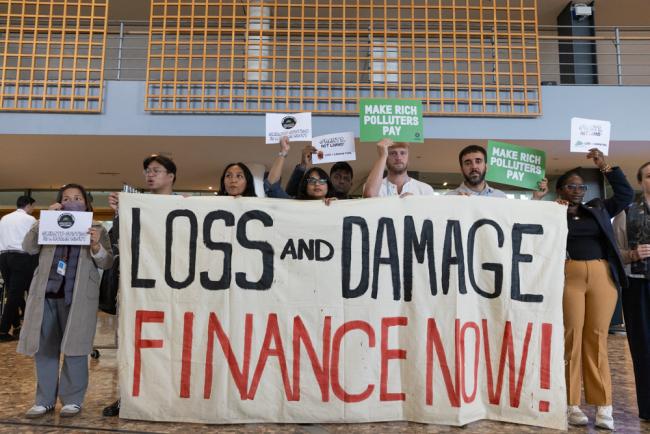 Members of civil society demonstrate in the corridors, calling for loss and damage finance that comes in the form of grants, not loans