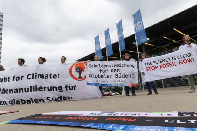 Members of the Scientist Rebellion movement demonstrate outside the venue as delegate queue for the first day of SB 60