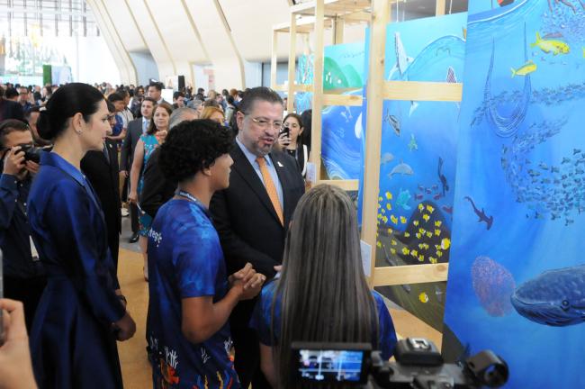 Local youth show their paintings to Rodrigo Chaves Robles, President of Costa Rica, and Signe Zeikate, First Lady of Costa Rica