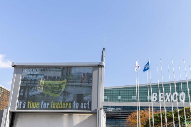 As negotiations continue behind closed doors, signs outside of the venue call for leaders to act and produce a strong treaty to address plastic pollution