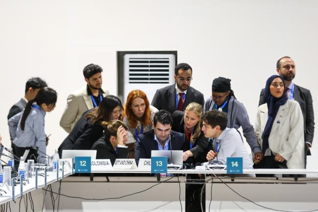 Delegates in a huddle during technical consultations on the Poznan Strategic Programme on Technology Transfer