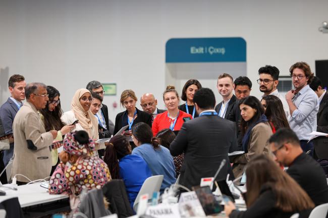Delegates in a huddle during informal consultations on the work programme under Paris Agreement Article 6.8 (non-market approaches)