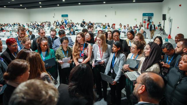 Delegates in a huddle during informal consultations on research and systematic observation