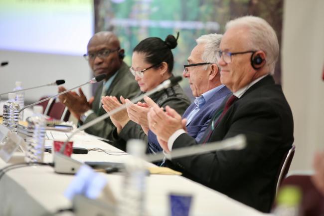 The dais applaud during the conclusion of the Committee session.