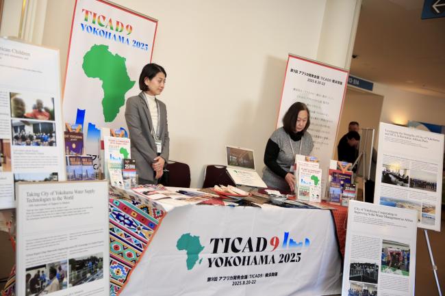 A TICAD9 Yokohama 2025 booth showcasing African development initiatives with representatives and informational displays.