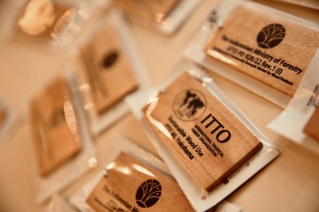 Wooden name tags featuring ITTO and partner logos, displayed at the ITTC60 session.