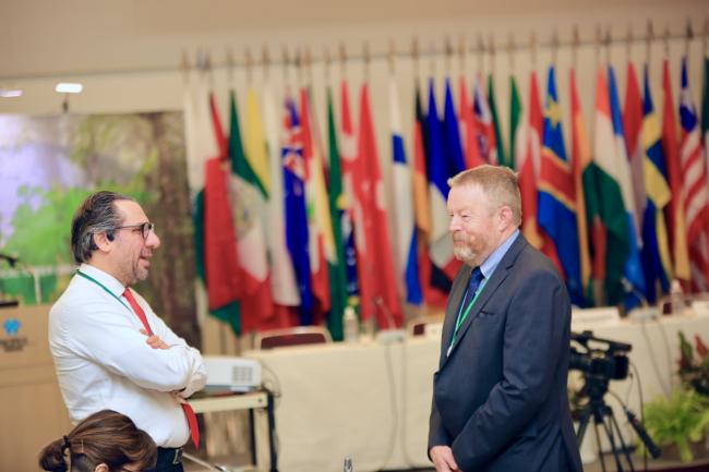 Two participants share a light moment during the ITTC60 session, fostering connections amid discussions on forestry and sustainability.