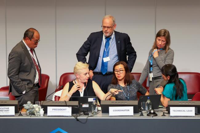 Rolph Payet, Executive Secretary, BRS Conventions, and Stockholm Convention COP12 President Maya Berci, conferring with members of the BRS Secretariat