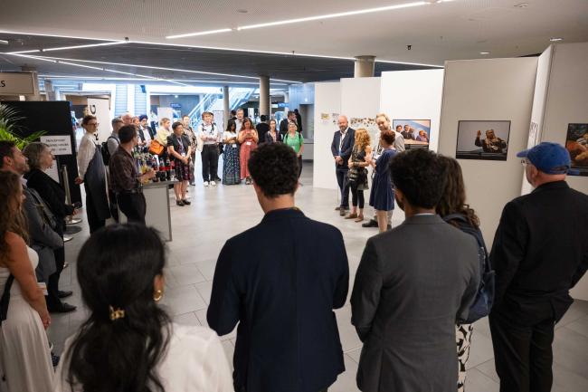 Delegates gather for the official opening of the photography exhibition 'Finding Common Ground', which offers a glimpse into the quieter, yet powerful moments of human connection during climate negotiations, highlighting the important role of multilateralism