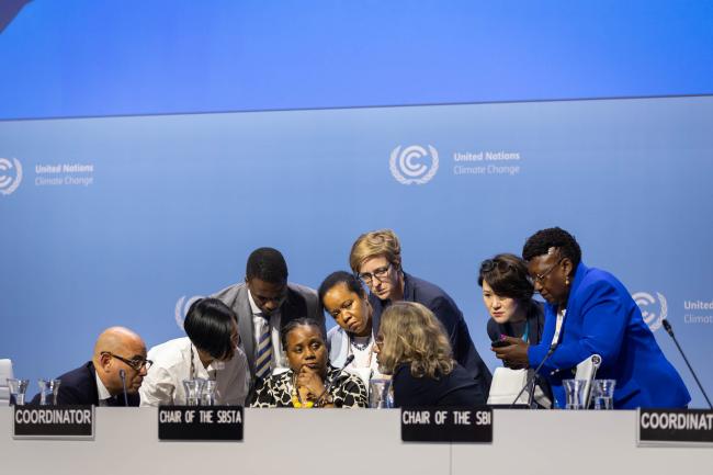 As plenary is suspended, members of the UNFCCC Secretariat consult on the dias