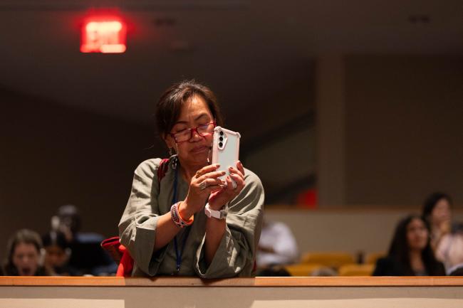 A delegate photographs speakers from the gallery