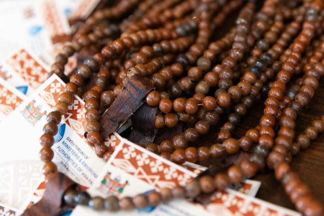 Badges are made entirely from traditional materials, including handmade clay beads and fasteners made from tree bark