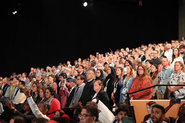 Participants stand during the hearing of the national anthem of UAE. 