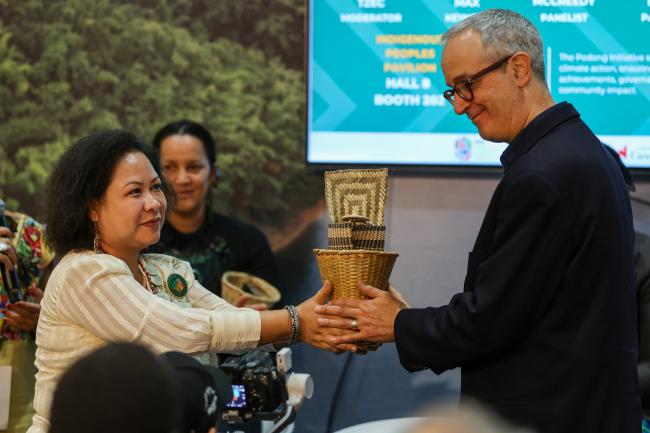 Mya Mya Nue, Advisor, Gender and Community Cohesion, GRAUS Indigenous Organization, handing a basket (Podong) to Kerry Max, Deputy Director, Partnering for Climate, Global Affairs Canada