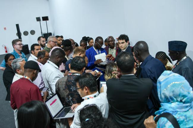 Delegates huddle during informal consultations on linkages between the Technology Mechanism and the Financial Mechanism