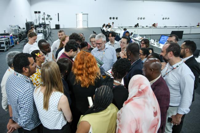 Delegates forming and huddle during informal consultations on matters relating to technology development and transfer