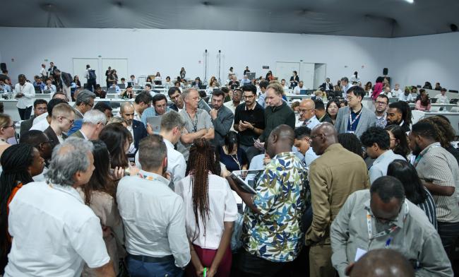 Delegates huddle during informal consultations on the Paris Agreement Article 6.4 mechanism