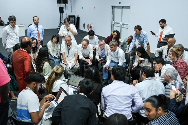 Delegates huddle during informal consultations on budgetary matters relating to the Kyoto Protocol's International Transaction Log (ITL)