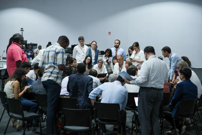 Delegates huddle during informal consultations on budgetary matters relating to the Kyoto Protocol's International Transaction Log (ITL)