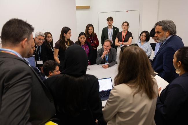 Delegates huddle during the informal consultations on cooperation from other international organizations