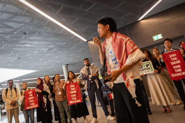 Members of civil society demonstrate, calling to 'end genocide everywhere', highlighting the link between militarism, military spending, and climate justice