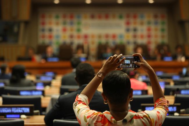 A delegate takes a photo of the dais during the discussion on African countries, Least Developed Countries and Landlocked Developing Countries